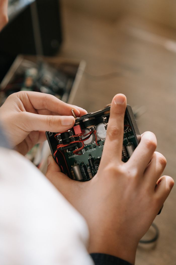 The Art of Drawing Readers In: Your attractive post title goes here Close-up of hands repairing an electronic circuit board indoors, demonstrating electronics engineering.